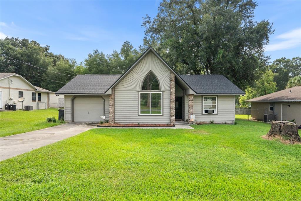 A single-story house with light gray siding, a peaked roofline, and an attached garage — 9 TEAK COURT, OCALA, FL