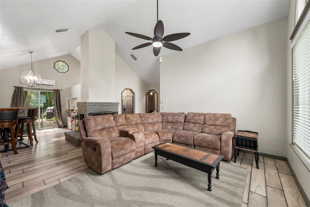 A living room features a brown sectional sofa, a coffee table, and a stone fireplace — 9 TEAK COURT, OCALA, FL