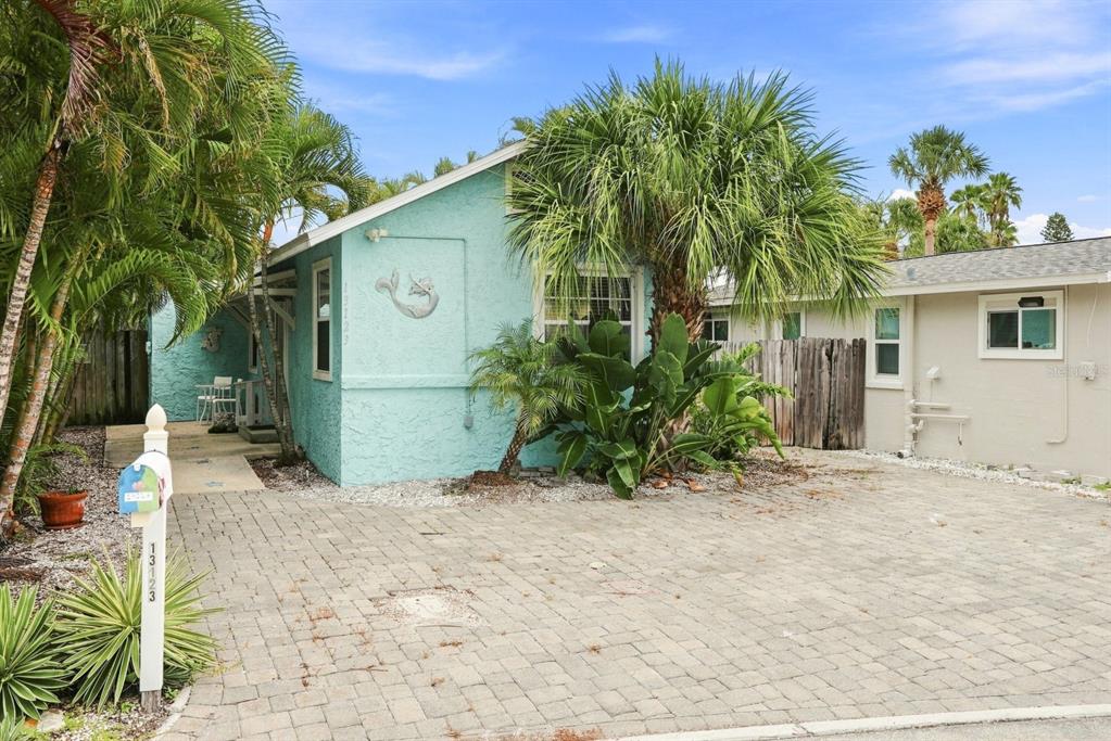 A light blue house with a paver driveway and a large palm tree in front — 13123 4TH STREET E, MADEIRA BEACH, FL