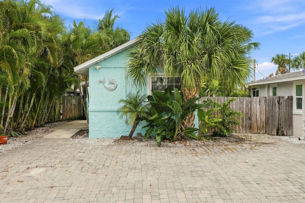 A light blue house exterior features a paved driveway, palm trees, and a wooden fence — 13123 4TH STREET E, MADEIRA BEACH, FL