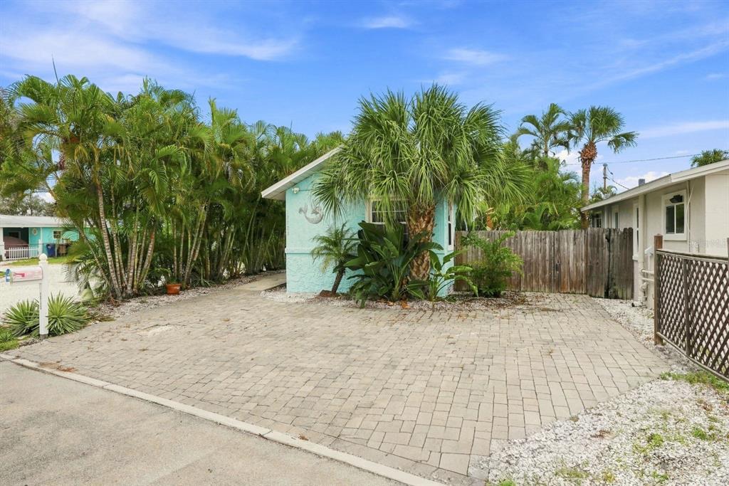 A light blue house with a paved driveway and palm trees under a blue sky — 13123 4TH STREET E, MADEIRA BEACH, FL