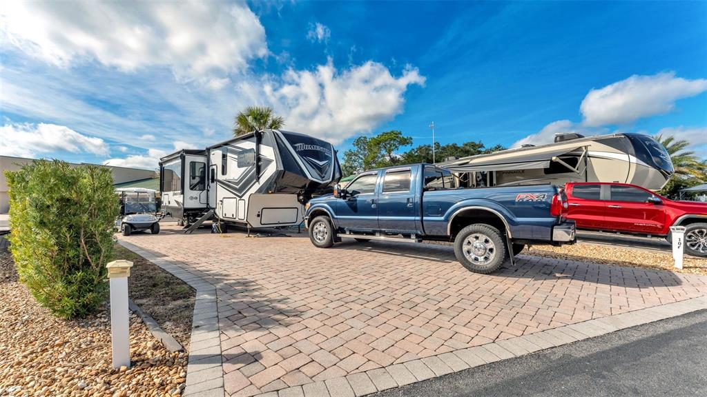 A blue pickup truck is parked on a paved driveway next to two large RVs — 16404 BAY STREET, CLERMONT, FL