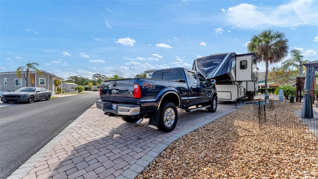 A dark blue pickup truck is hitched to a fifth-wheel trailer on a paved driveway — 16404 BAY STREET, CLERMONT, FL