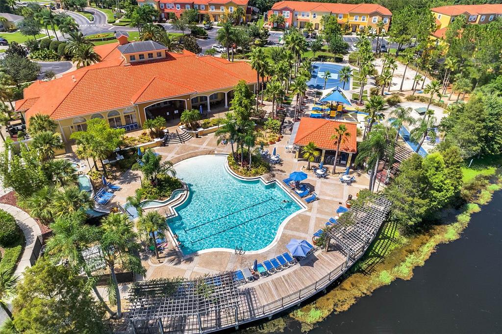An aerial view shows a community swimming pool and hot tub beside a large lake — 4733 VERO BEACH PLACE, KISSIMMEE, FL