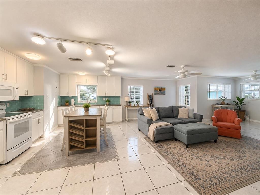 An open-concept kitchen and living area features white cabinets, a central island, and tile flooring — 1205 LISA LANE, OKEECHOBEE, FL