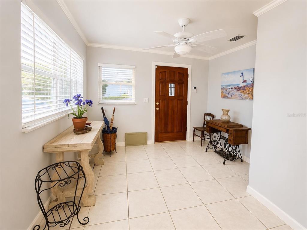 An entryway features light tile flooring, a wooden front door, and two vintage-style console tables — 1205 LISA LANE, OKEECHOBEE, FL