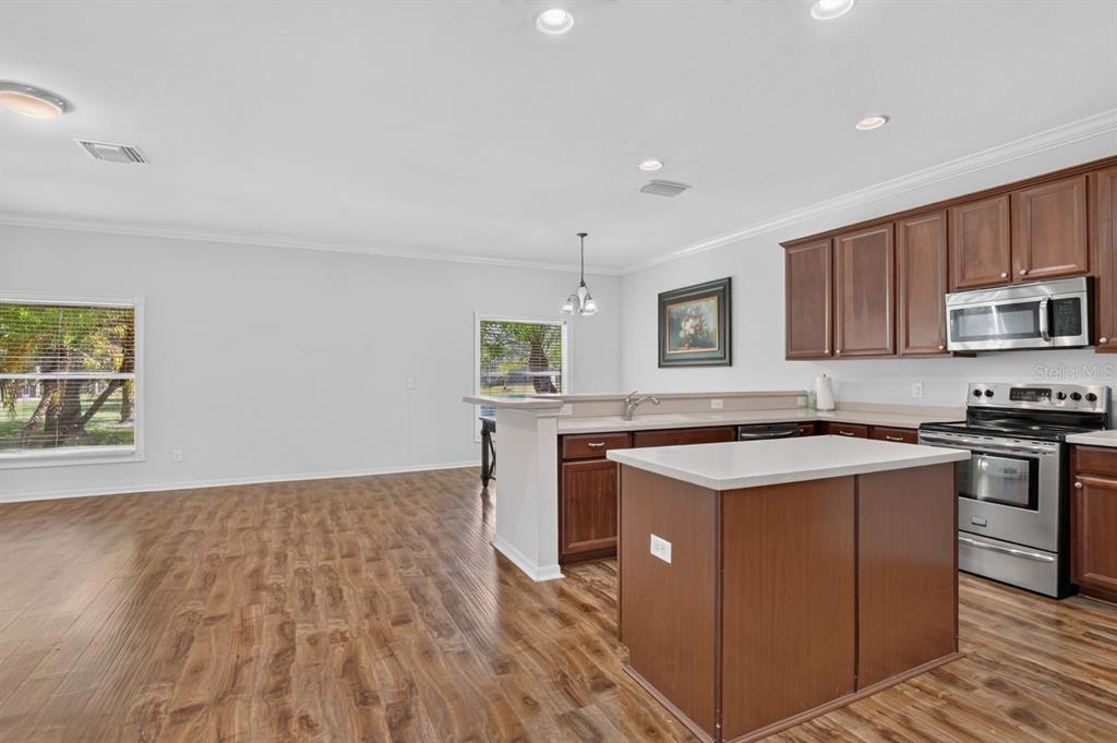 A kitchen with a center island, dark wood cabinets, and stainless steel appliances — 8083 SILVER BIRCH WAY, LEHIGH ACRES, FL