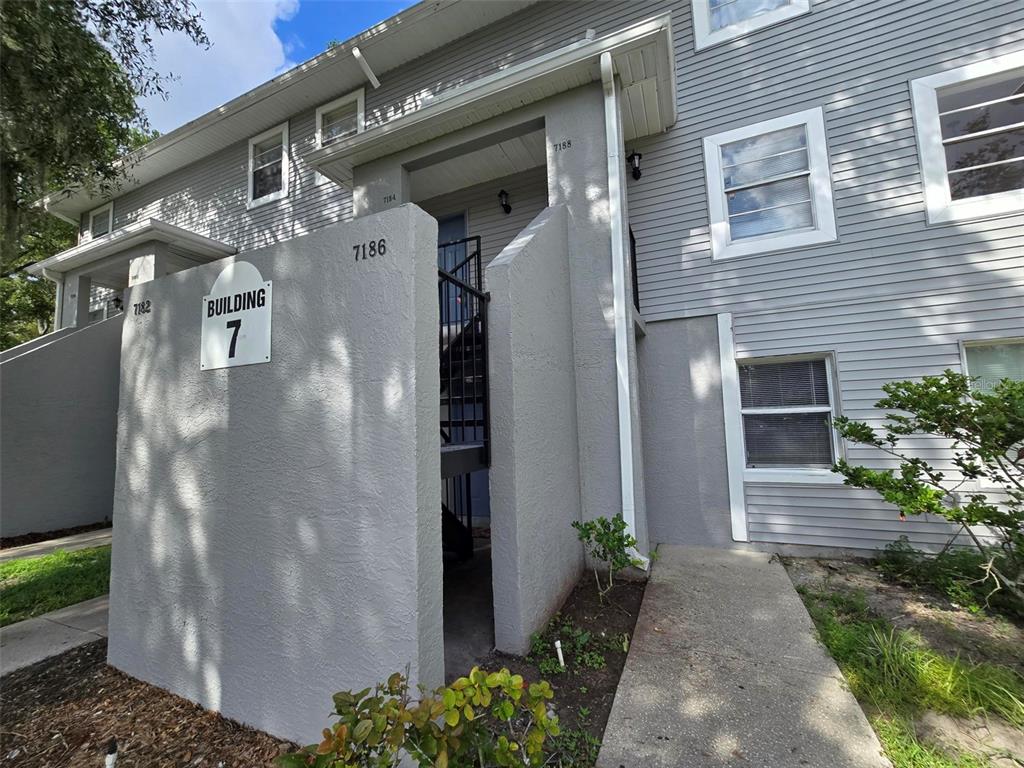 A gray multi-story apartment building features a prominent sign labeled Building 7 and exterior stairs — 7186 E BANK DRIVE UNIT 7186, TAMPA, FL