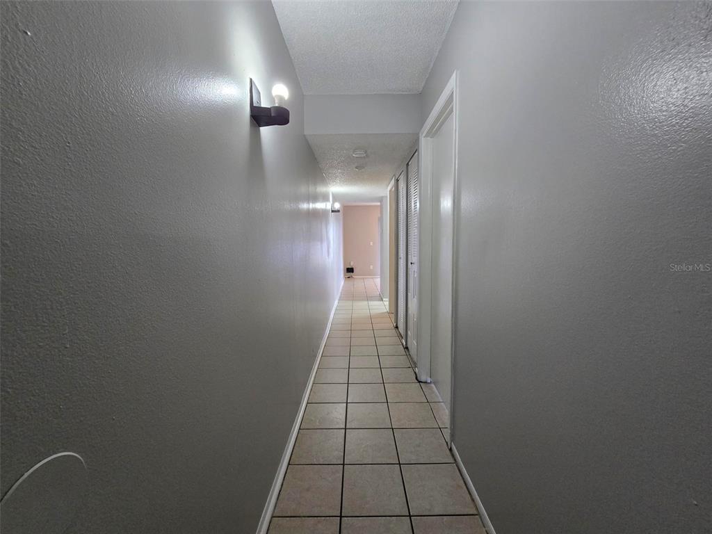 A long hallway features light gray walls, white trim, and light-colored square floor tiles — 7186 E BANK DRIVE UNIT 7186, TAMPA, FL