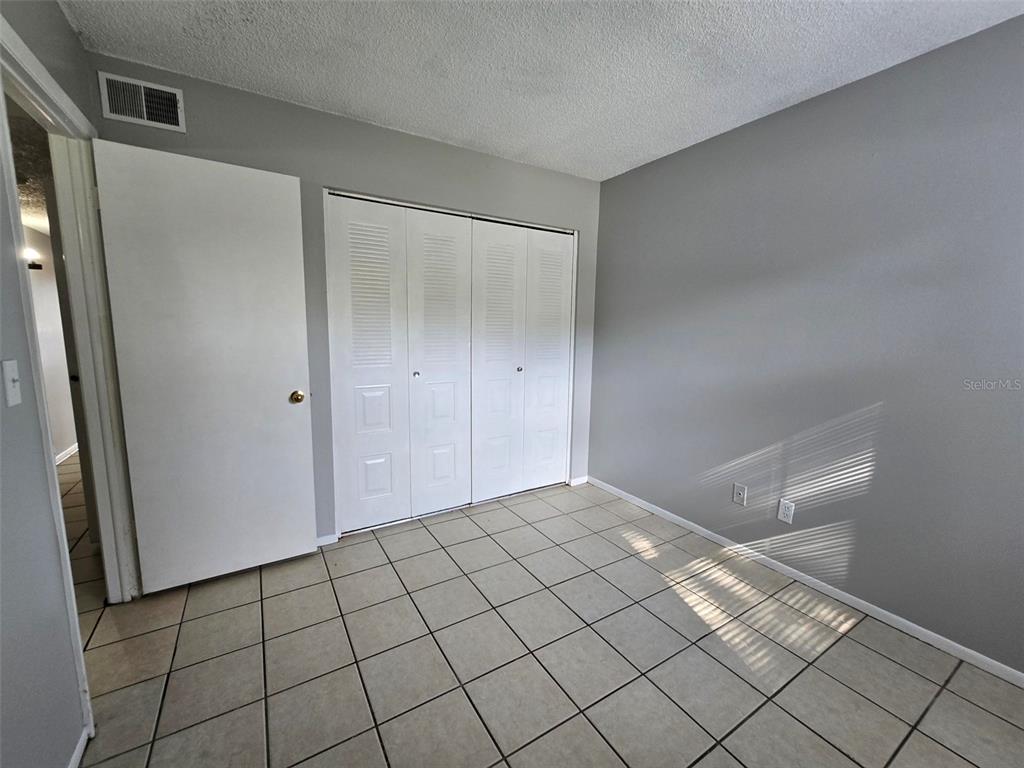 A bedroom with gray walls, tiled flooring, and white bifold closet doors — 7186 E BANK DRIVE UNIT 7186, TAMPA, FL