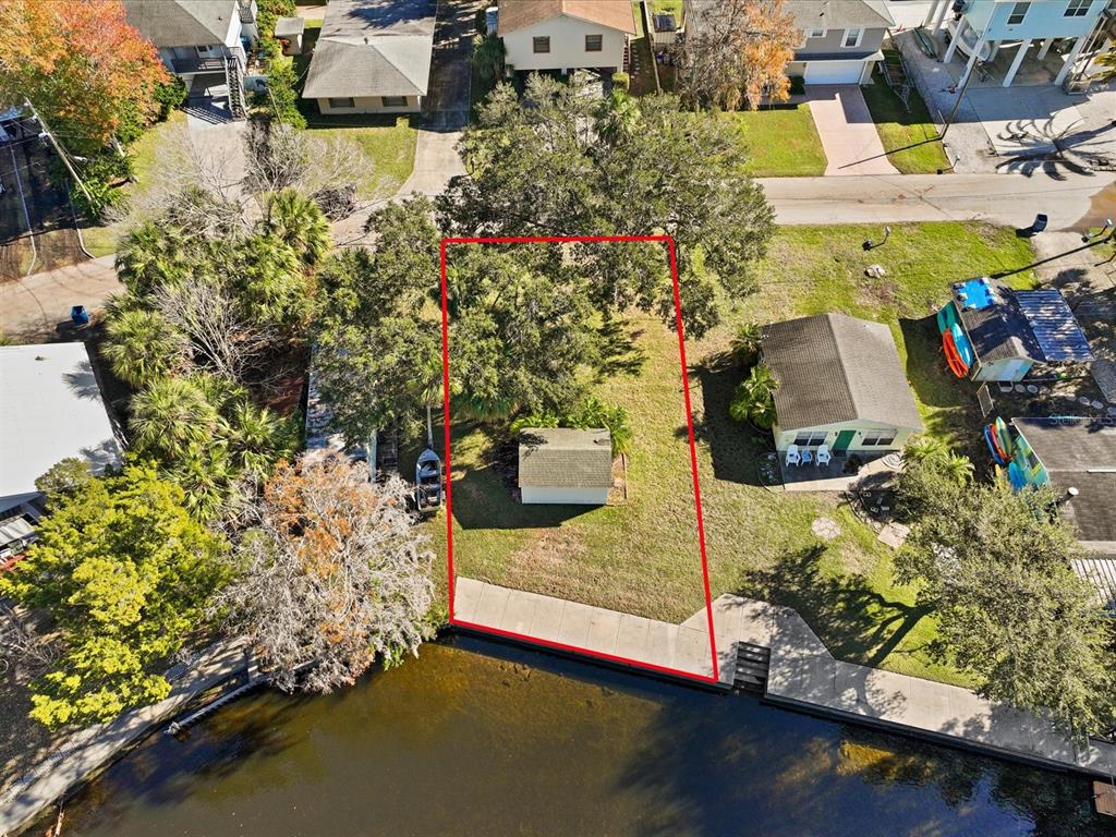 An aerial view shows a waterfront lot with a small shed and mature trees — 7259 TROPICAL DRIVE, WEEKI WACHEE, FL