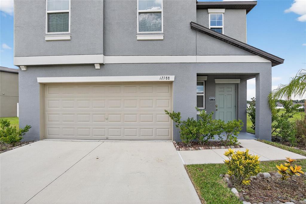 A two-story gray house features a two-car garage and a covered front entryway — 12788 MAPLE BONSAI DRIVE, RIVERVIEW, FL
