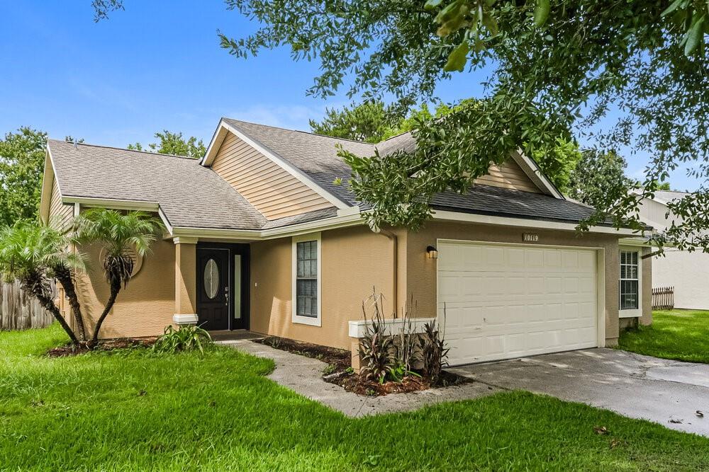 A tan, single-story suburban house with a two-car garage and a front walkway — 10119 PINK CARNATION COURT, ORLANDO, FL