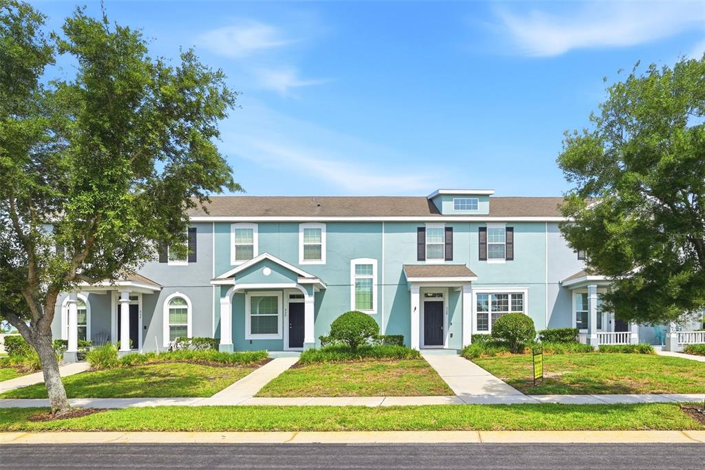 A row of light blue townhouses with white trim, covered porches, and green lawns — 528 RAINBOW SPRINGS LOOP, GROVELAND, FL