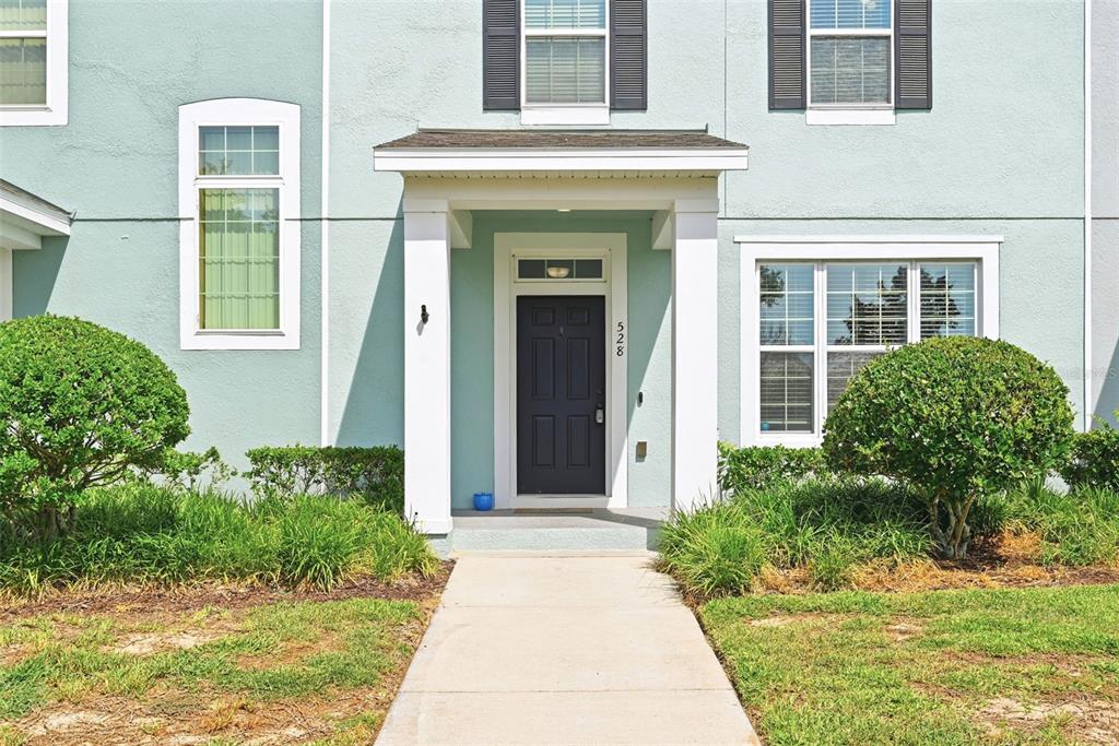 A light blue two-story house features a dark front door and a concrete walkway — 528 RAINBOW SPRINGS LOOP, GROVELAND, FL