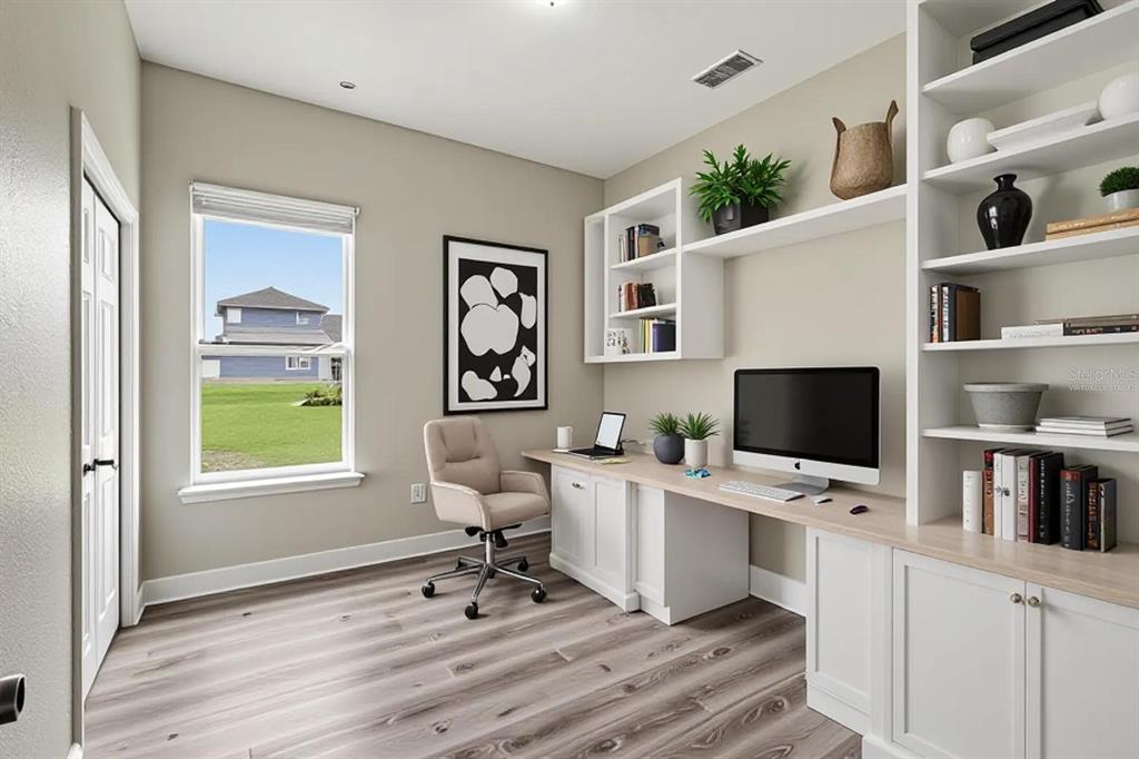 A home office features built-in white shelving, a desk, a rolling chair, and wood-look flooring — 200 LAKE ARIETTA COURT, AUBURNDALE, FL