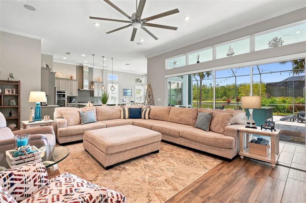 A living room features a large sectional sofa, a built-in media center, and a ceiling fan — 4093 EPIC COVE, LAND O LAKES, FL