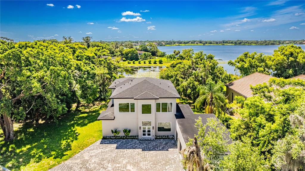 An aerial view shows a two-story house with a paved driveway near a lake — 436 E 7TH AVENUE, WINDERMERE, FL