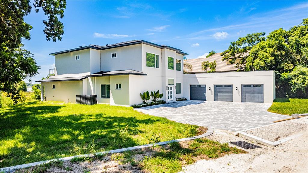 A modern two-story house features a light-colored exterior, a three-car garage, and a paved driveway — 436 E 7TH AVENUE, WINDERMERE, FL