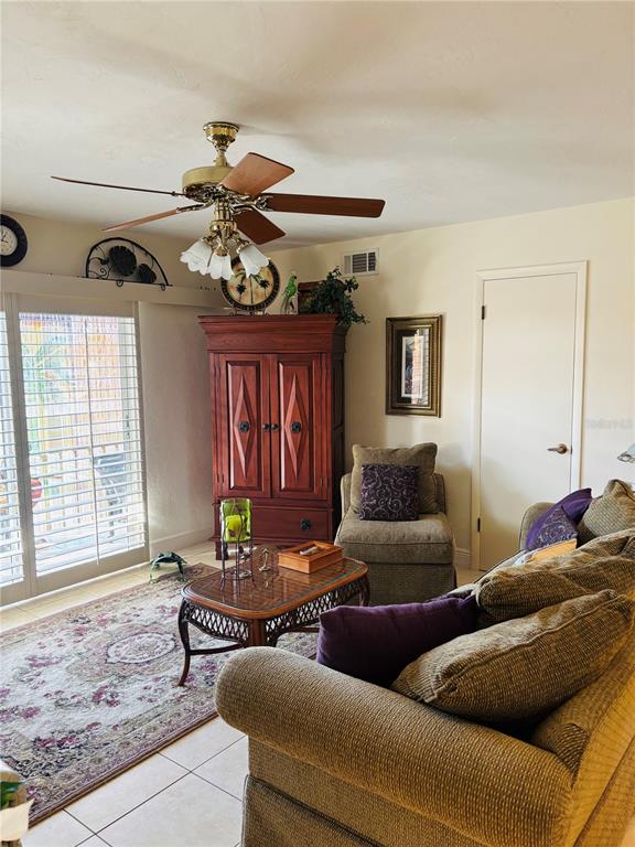 A living room features a ceiling fan, a wooden armoire, a patterned rug, and furniture — 1640 JUNO TRAIL UNIT 205-F, ASTOR, FL