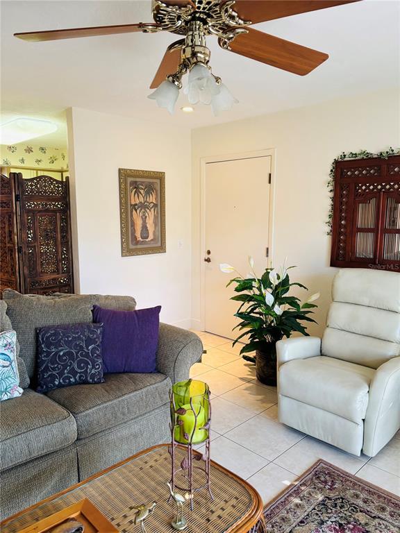 A living room features a ceiling fan, a sofa with purple pillows, and a recliner — 1640 JUNO TRAIL UNIT 205-F, ASTOR, FL