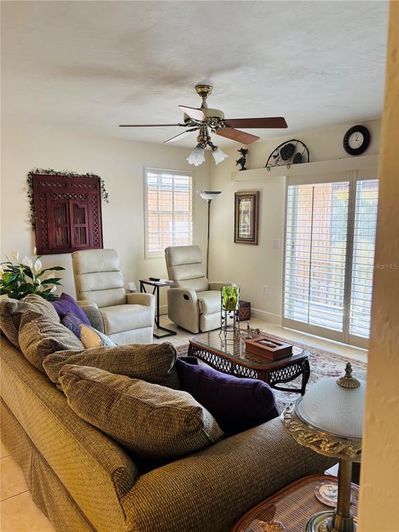 A living room features a textured sofa, two beige recliners, a coffee table, and a ceiling fan — 1640 JUNO TRAIL UNIT 205-F, ASTOR, FL
