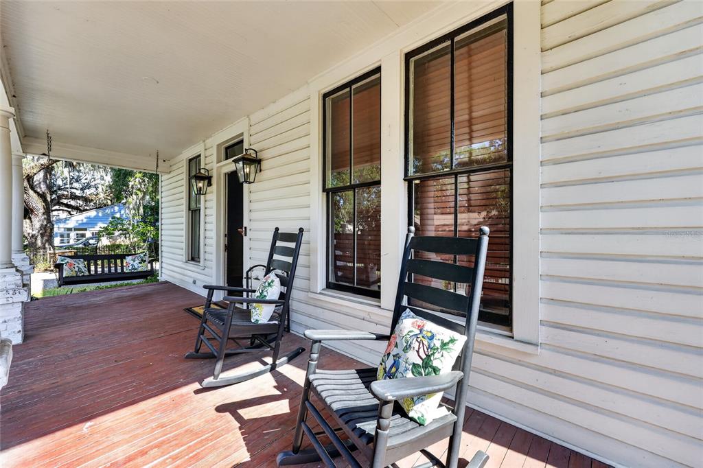 A wooden front porch features two rocking chairs, a hanging swing, and white siding — 819 SE 2ND STREET, OCALA, FL