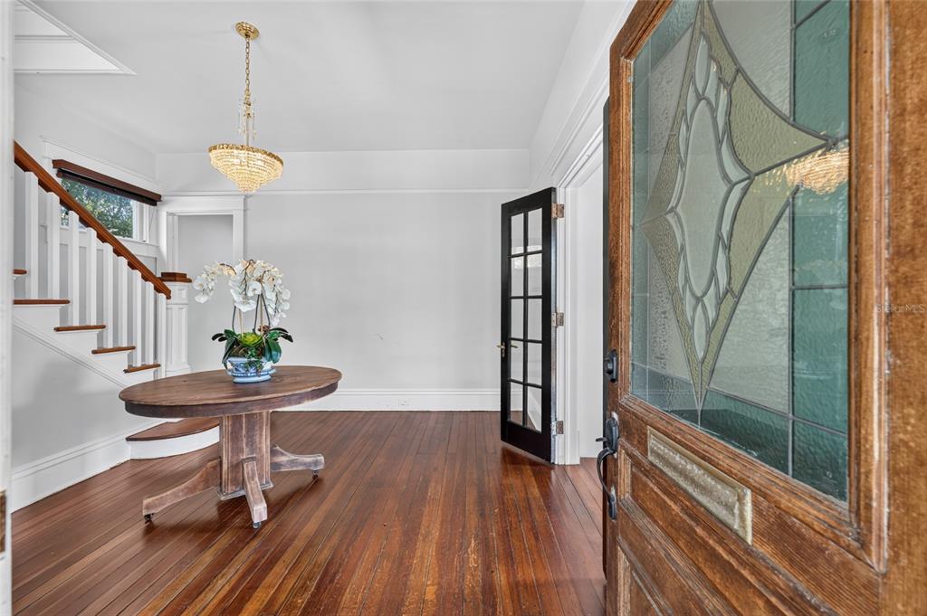 An entryway features a wooden staircase, a round table with flowers, and a glass-paneled door — 819 SE 2ND STREET, OCALA, FL