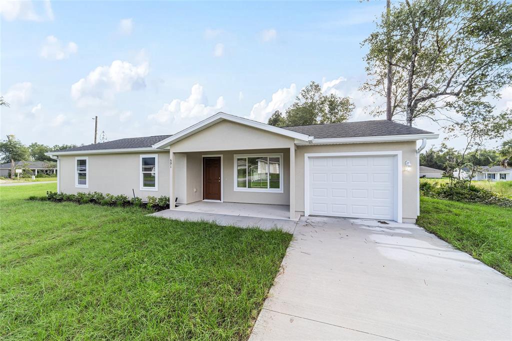 A single-story house with light-colored siding, a covered porch, and an attached garage — 23827 SW BEAVER DRIVE, DUNNELLON, FL