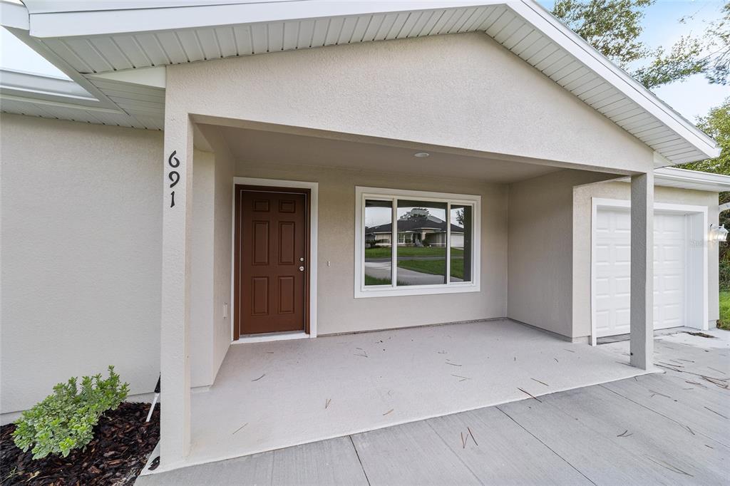 A single-story house with a beige exterior, a front porch, and an attached garage — 23827 SW BEAVER DRIVE, DUNNELLON, FL