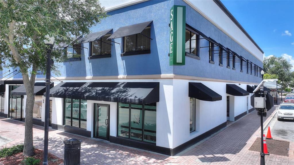 A two-story blue and white commercial building with black awnings sits on a brick sidewalk — 55 NW 3RD STREET NW, WINTER HAVEN, FL