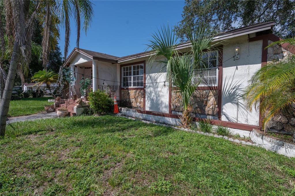 A single-story house with white stucco walls, stone accents, and a front porch — 5104 N 34TH STREET, TAMPA, FL