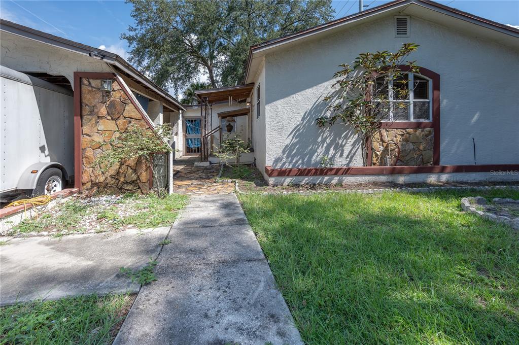 A concrete walkway leads to the entrance of a house with stone accents and stucco — 5104 N 34TH STREET, TAMPA, FL