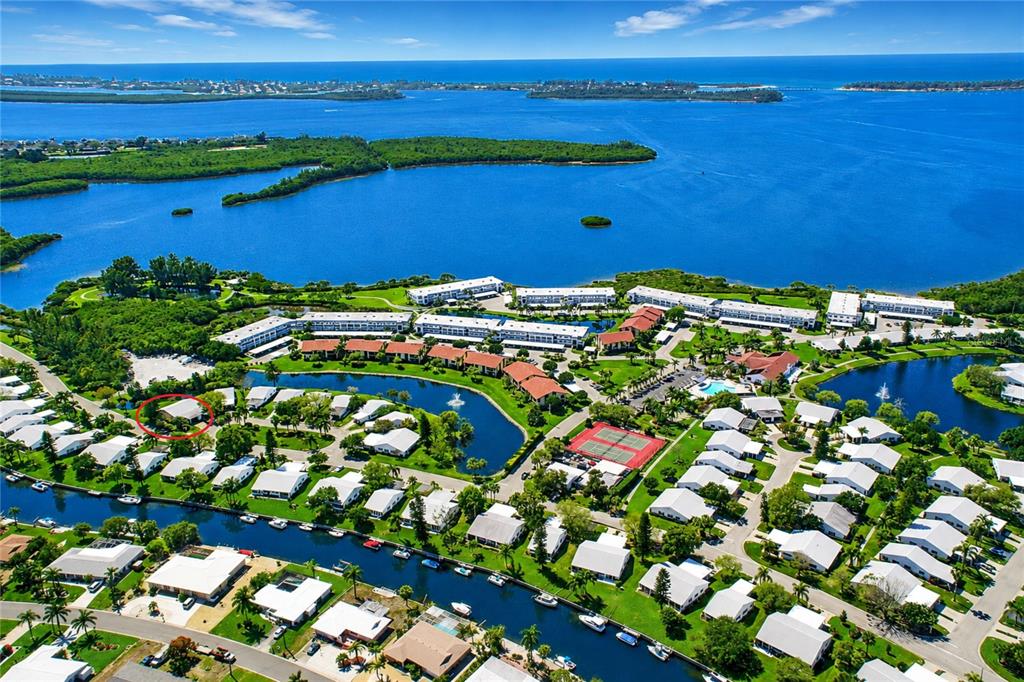 An aerial view shows a single-story house with a carport in a waterfront neighborhood — 4726 POTOMAC CIRCLE, BRADENTON, FL