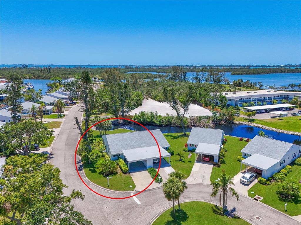 An aerial view shows a coastal residential community with apartment buildings and houses near water — 4726 POTOMAC CIRCLE, BRADENTON, FL