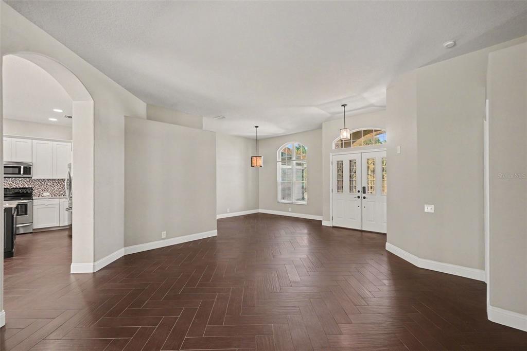 An open-concept living area features dark wood herringbone floors, white walls, and double entry doors — 11920 OAK RIDGE DRIVE, PARRISH, FL