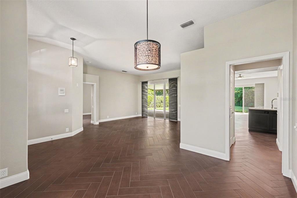 An open living area features dark herringbone-patterned flooring, a decorative pendant light, and sliding doors — 11920 OAK RIDGE DRIVE, PARRISH, FL