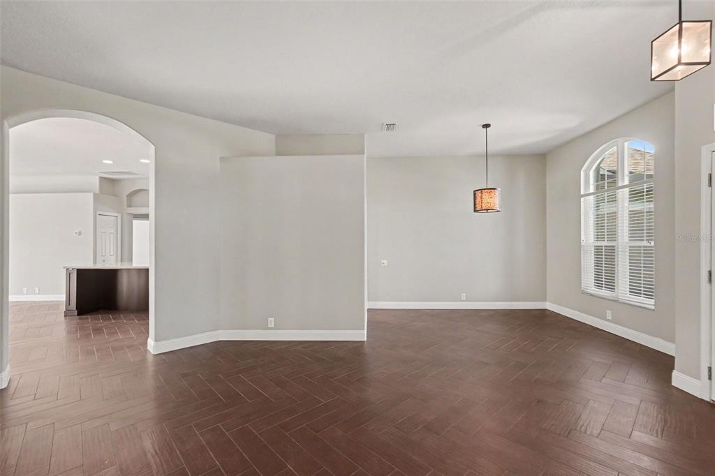 An empty room with dark herringbone wood flooring, neutral walls, and a large arched window — 11920 OAK RIDGE DRIVE, PARRISH, FL
