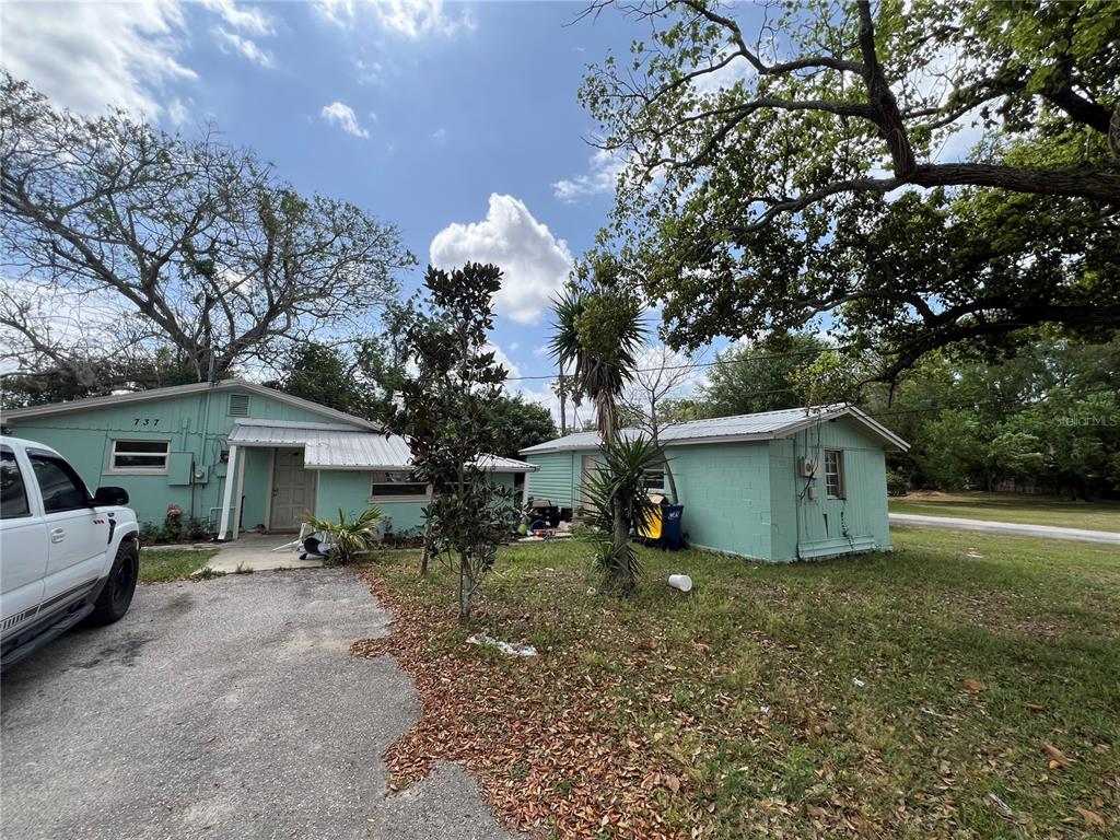 A light green house with a metal roof and a driveway under large trees — 737 ALBROOK STREET, MASCOTTE, FL