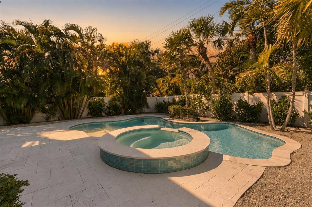 A backyard swimming pool with an integrated circular spa surrounded by light-colored stone pavers — 418 MAGNOLIA AVENUE, ANNA MARIA, FL
