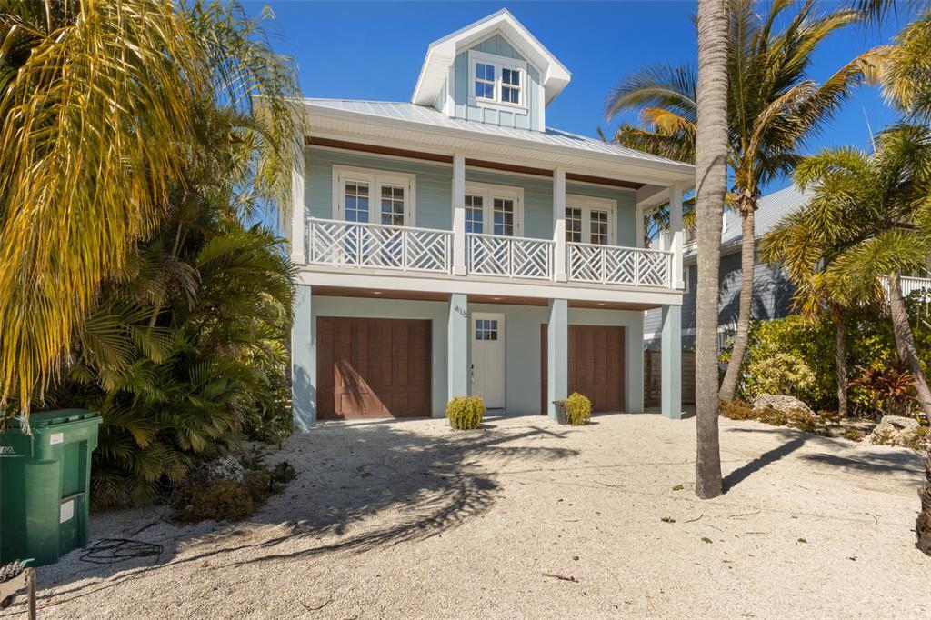 A two-story coastal house with a metal roof, balcony, and two garage doors — 418 MAGNOLIA AVENUE, ANNA MARIA, FL