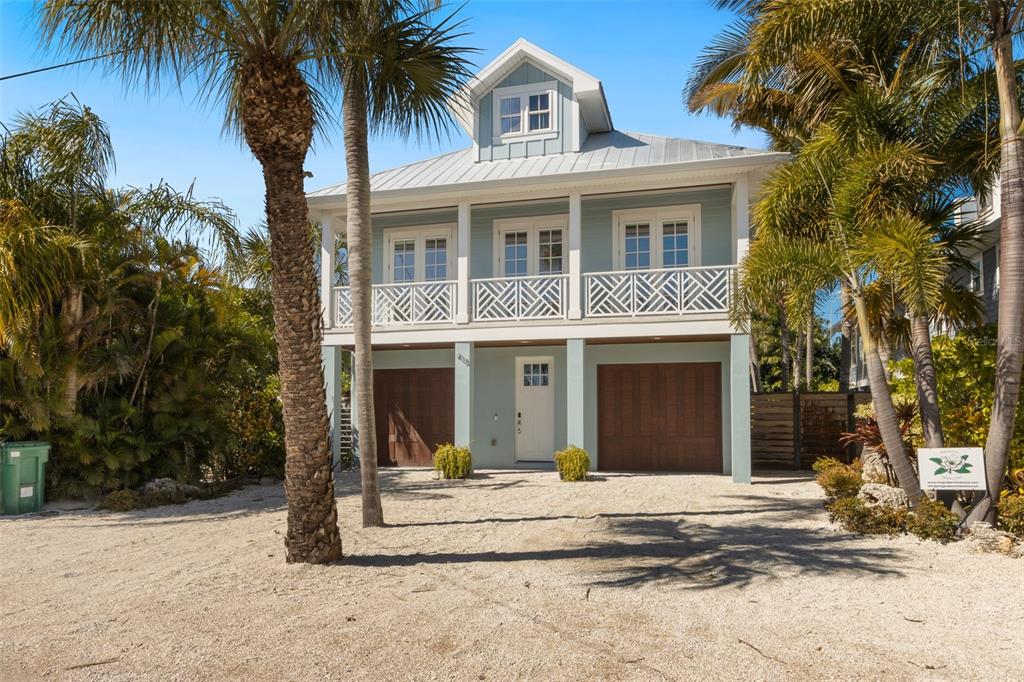 A living room features a vaulted ceiling, two sofas, a television, and a sliding glass door — 418 MAGNOLIA AVENUE, ANNA MARIA, FL