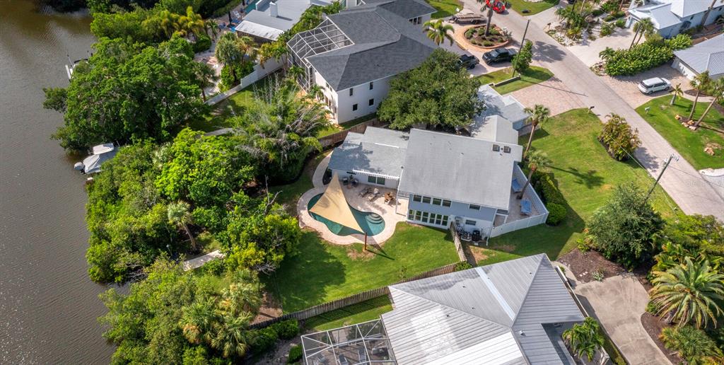 An aerial view shows a house with a pool, a shade sail, and waterfront access — 430 ISLAND CIRCLE, SARASOTA, FL