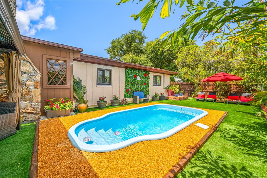 A backyard features a small swimming pool surrounded by yellow gravel and artificial turf — 1488 LACONIA DRIVE E, CLEARWATER, FL