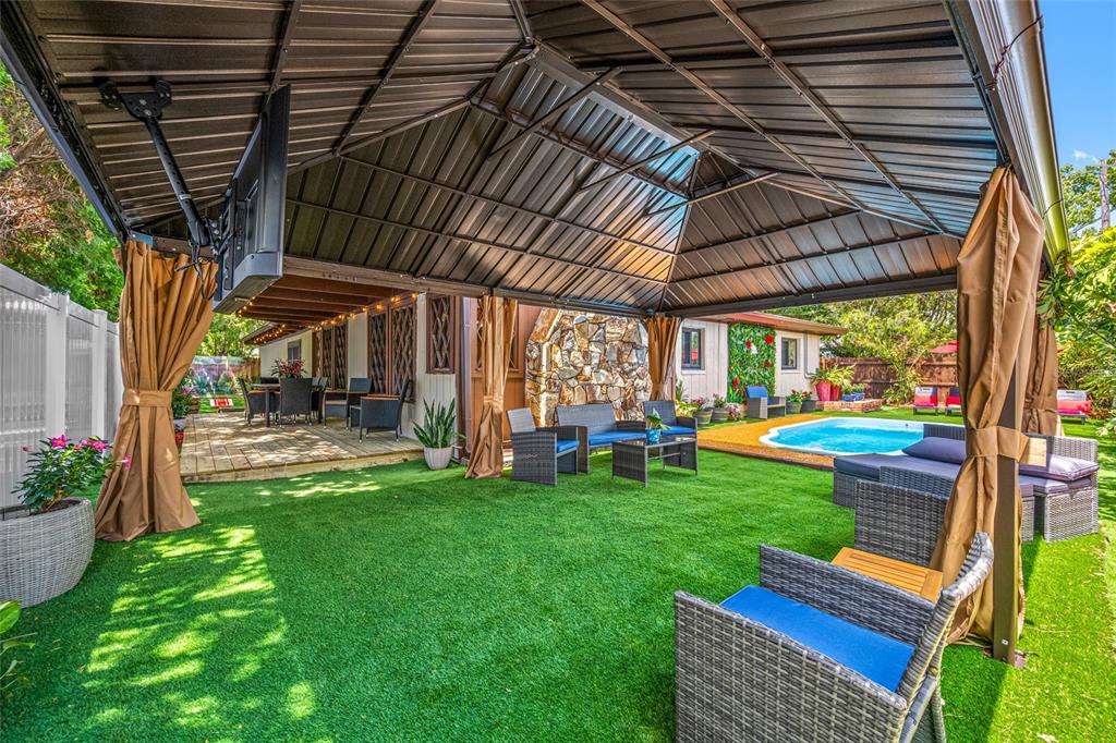 A covered outdoor patio with artificial turf, wicker furniture, and a swimming pool — 1488 LACONIA DRIVE E, CLEARWATER, FL