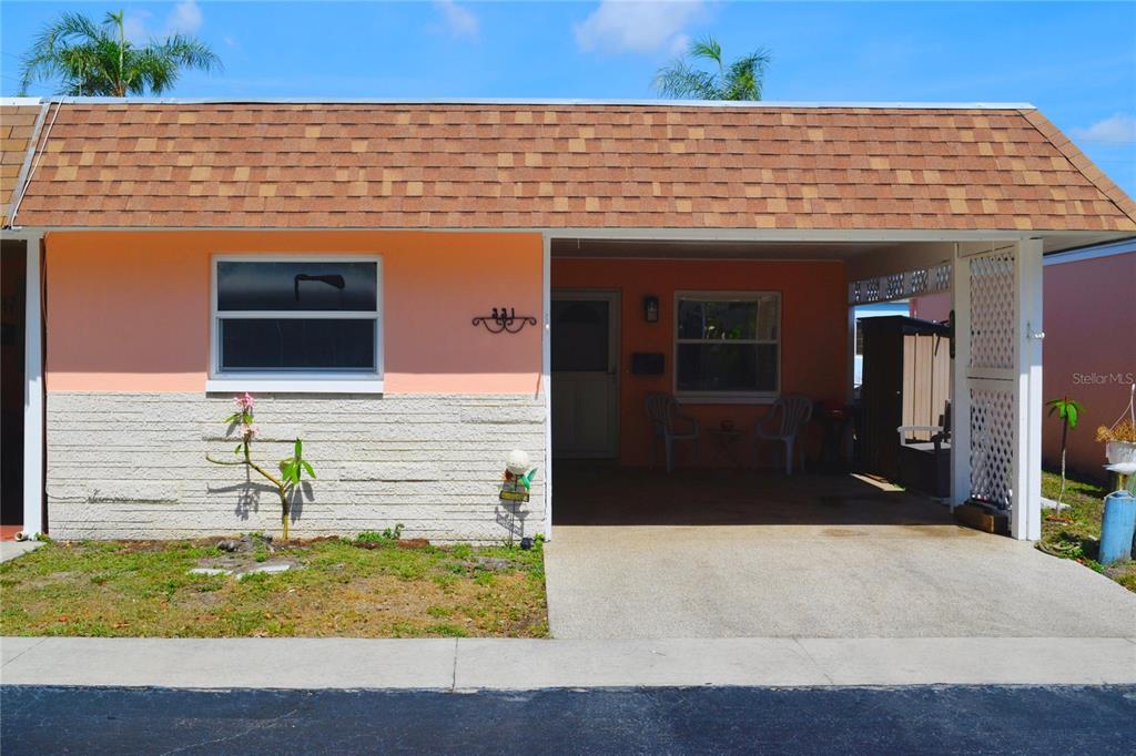 A single-story house with a peach-colored exterior, a stone-textured base, and an attached carport — 331 SKY LOCH DRIVE W, DUNEDIN, FL