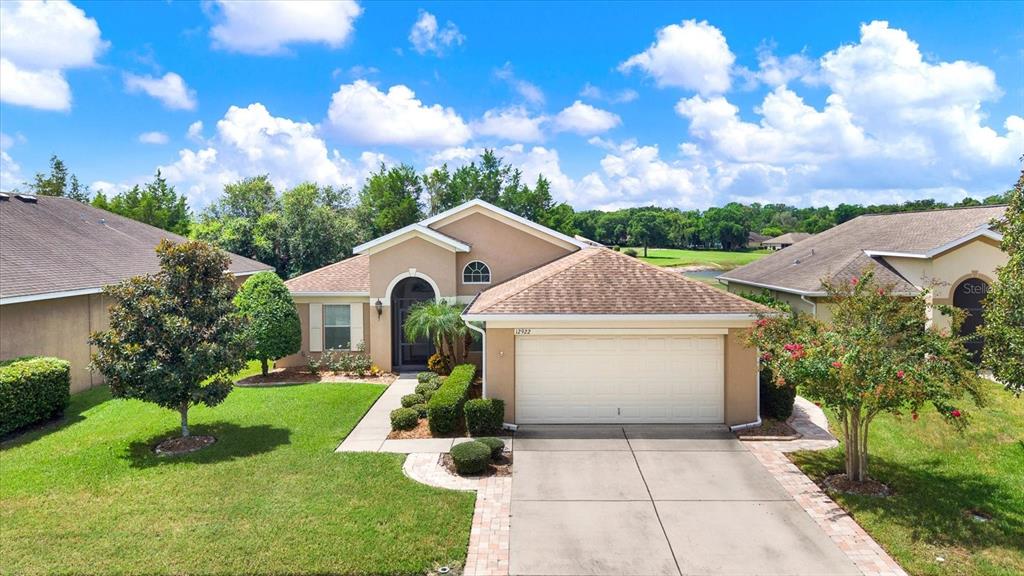 An exterior view of a single-story suburban house with a two-car garage and lawn — 12922 PAYNE STEWART WAY, HUDSON, FL