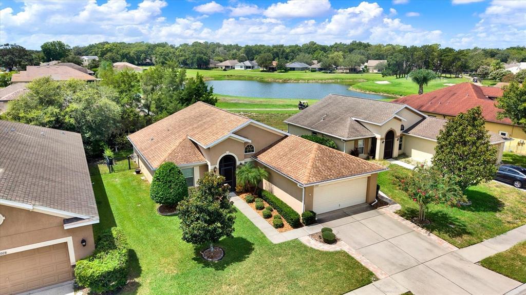 An aerial view shows a suburban house with a tan exterior, brown roof, and driveway — 12922 PAYNE STEWART WAY, HUDSON, FL