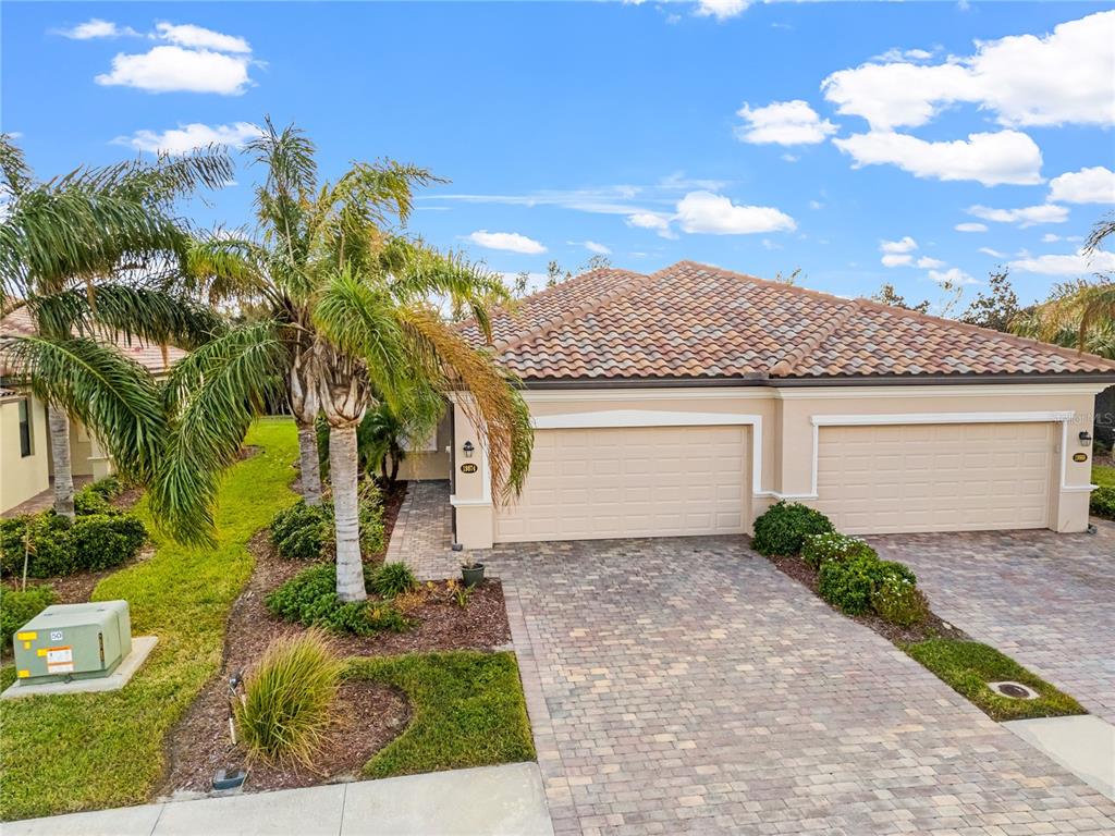 A single-story house with a tiled roof, two garage doors, and a paved driveway — 19874 BENISSIMO DRIVE, VENICE, FL