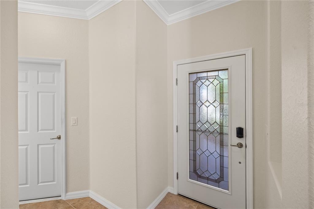 An entryway features a white front door with a decorative glass insert and tile flooring — 19874 BENISSIMO DRIVE, VENICE, FL
